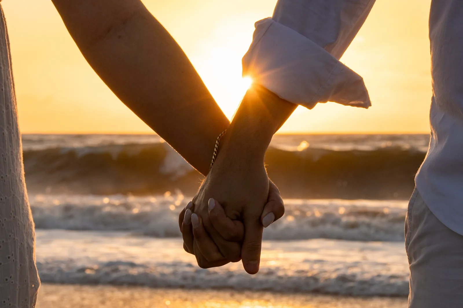 Casal de mãos dadas ao pôr do sol